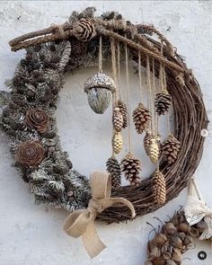 a wreath with pine cones and ornaments hanging from it's side on a wall