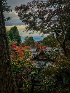 an old building in the middle of trees with fall foliage around it and mountains in the background