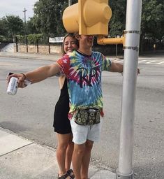 a man and woman standing next to a traffic light holding onto a water bottle in their hands