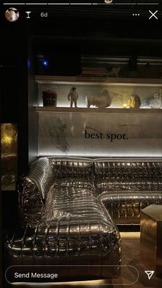 a couch and ottoman in front of a shelf with books on the wall behind it