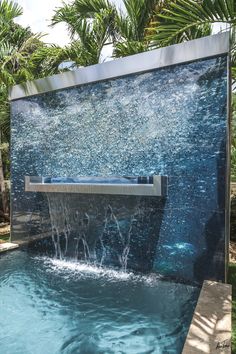 an outdoor fountain with water flowing from it's sides and palm trees in the background