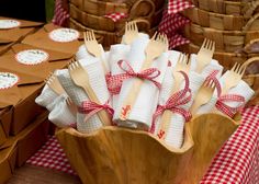 a wooden bowl filled with lots of white napkins next to brown baskets and forks