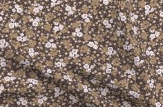 a brown and white flowered fabric with small white flowers on the top of it