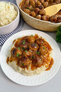 a plate with mashed potatoes, meatballs and gravy on it next to other dishes