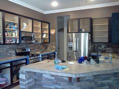 a kitchen with stone counter tops and stainless steel appliances in the back wall, along with built - in shelving