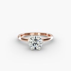 a rose gold engagement ring with a round brilliant cut diamond in the center, on a white background