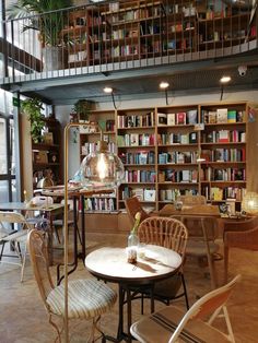 a room filled with lots of furniture and bookshelves next to a table in front of a window