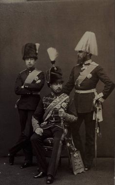 an old photo of two men in uniforms and one is sitting on a chair while another man stands next to him