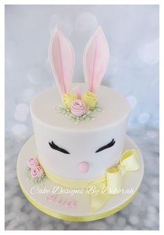 a white cake decorated with pink roses and bunny ears