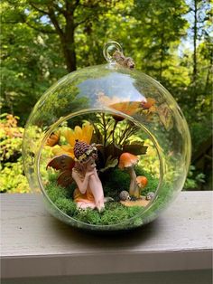 a glass ball with a fairy figurine in it on a window sill