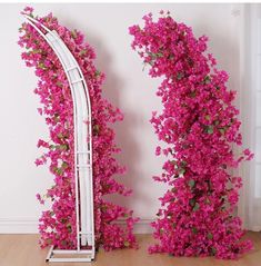 pink flowers are growing on the side of a white arch