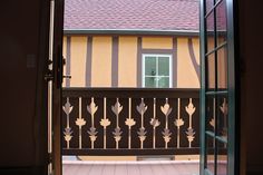 an open door leading to a balcony with flowers on the railing and a window in the background