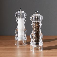 two salt and pepper mills sitting on top of a wooden table