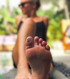 a person with a paw tattoo on their foot sitting in front of a swimming pool