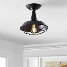 a black ceiling light hanging from the ceiling in a room with white walls and windows