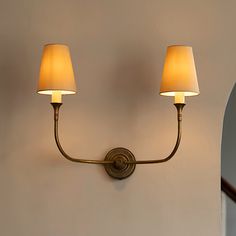 two lamps on the wall next to each other in front of a mirror and door