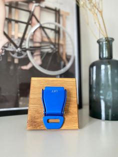 a wooden stand with a blue clip on it next to a vase and bicycle photograph