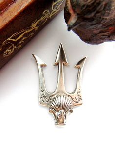 an antique silver brooch sits on a white surface next to a book and a cat