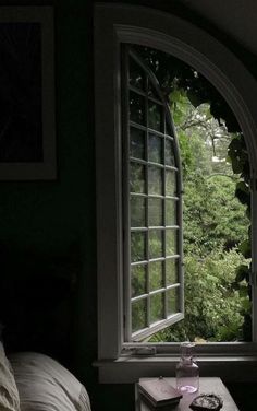 an open window in a dark room with a table next to it and a book on the side