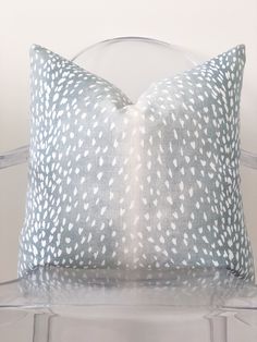 a white and blue pillow sitting on top of a clear chair