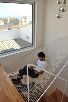 a man sitting on top of a bed under a window next to a wooden floor