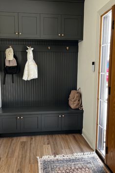 a coat rack with two coats hanging from it's hooks and a rug on the floor