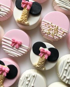 many decorated cookies with pink and white frosting on top of each one, including mickey mouse