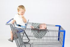 a little boy sitting in a shopping cart with a baby on it's back