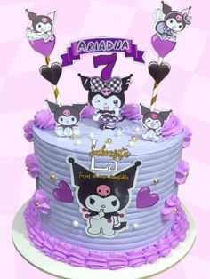 a birthday cake with purple icing and cats on the top is decorated with hearts