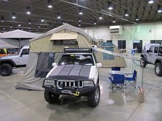 a truck with a tent attached to it parked in a garage next to other trucks