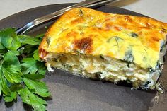 a piece of quiche on a plate with a fork and parsley next to it