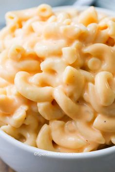 a white bowl filled with macaroni and cheese on top of a wooden table