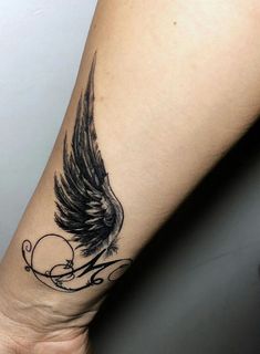 a woman's arm with an angel wing tattoo on it