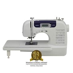 a white sewing machine sitting on top of a table next to a gold medal seal