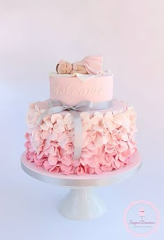 a pink and white cake with a baby on top