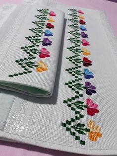 two placemats are sitting on top of each other, one has a cross stitch design