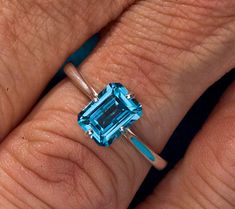 a woman's engagement ring with an aqua blue stone in the center and two diamonds on each side