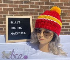 a mannequin wearing a red and yellow knitted hat next to a sign