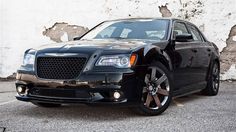 a black car parked in front of a white wall