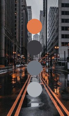 a city street with tall buildings and traffic lights on it's sides in the rain