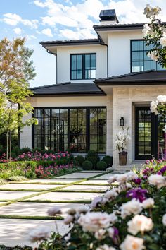 a white house with lots of windows and flowers in the front yard