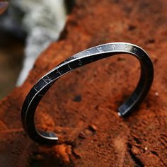 a silver bracelet sitting on top of a red rock