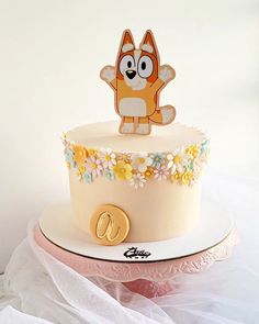 there is a cake that has a dog on top and flowers in the bottom tier