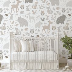 a baby's room with a white crib and wallpaper that has woodland animals on it