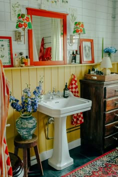 a white sink sitting next to a wooden dresser under a mirror on top of a wall