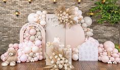 a table topped with lots of balloons next to a wall covered in pink and white decorations