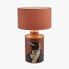 a lamp that has a bird on it with a bow tie around the neck and an orange shade