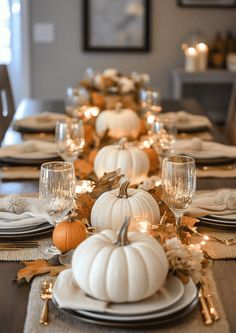 a dining room table set with white pumpkins and gold leaves on the place settings