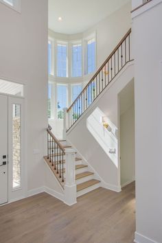 an empty room with white walls and wood floors is pictured in this image, there are stairs leading up to the second floor