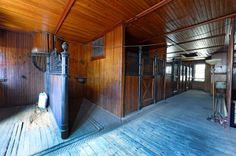 the inside of a horse barn with wooden floors and walls, including an iron gate